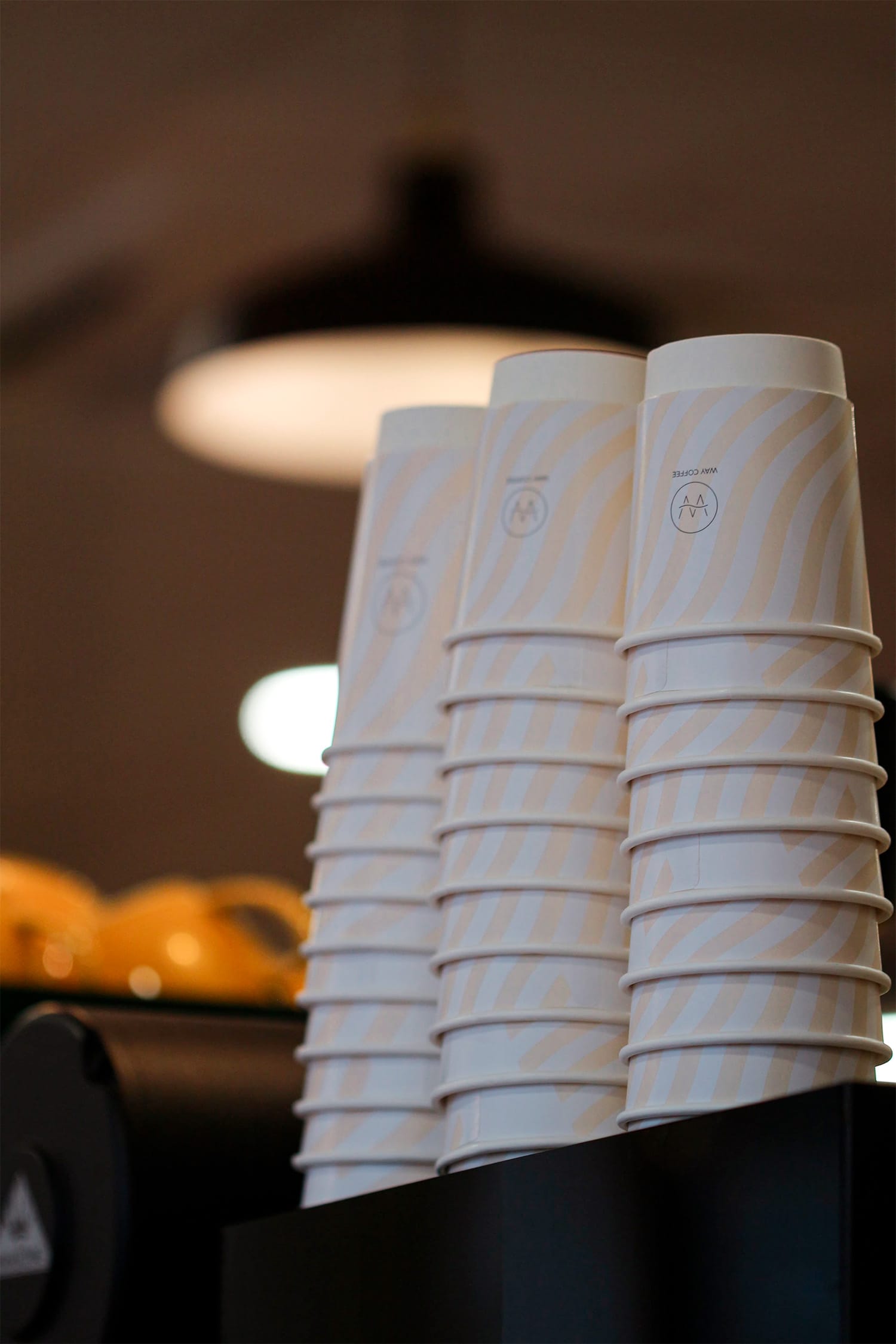 Photo taken at Way Coffee showing a stack of takeaway cups. This cup was designed with a subtle background pattern reinforcing the design motif.